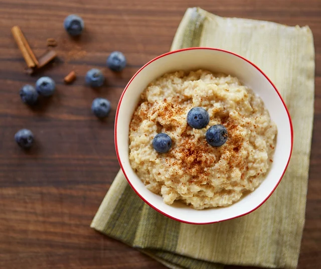 A warm bowl of oatmeal with blueberries on a wooden breakfast table